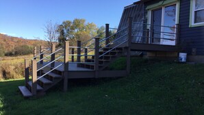 Un escalier en bois menant à une maison dont la rampe est en métal.