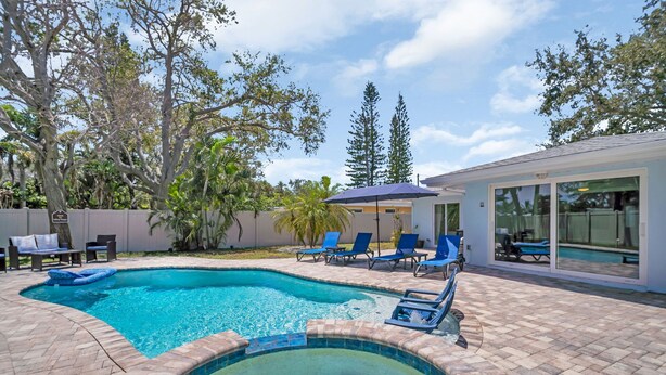 A swimming pool with a hot tub, surrounded by lounge chairs and a covered seating area.