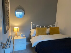 Cozy retreat with a white bed, round mirror, and bedside table.