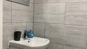 A bathroom with a white sink, a black cup, and a bottle of Palmolive soap. - Bridgend Central 2-bed Apartment (Bridgend)