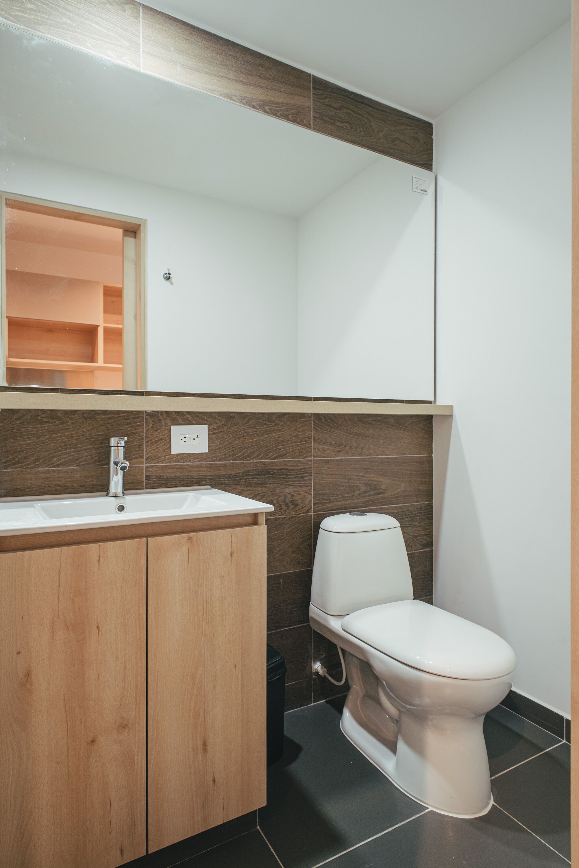 Une salle de bain moderne avec un meuble-lavabo en bois, un lavabo blanc et des toilettes.