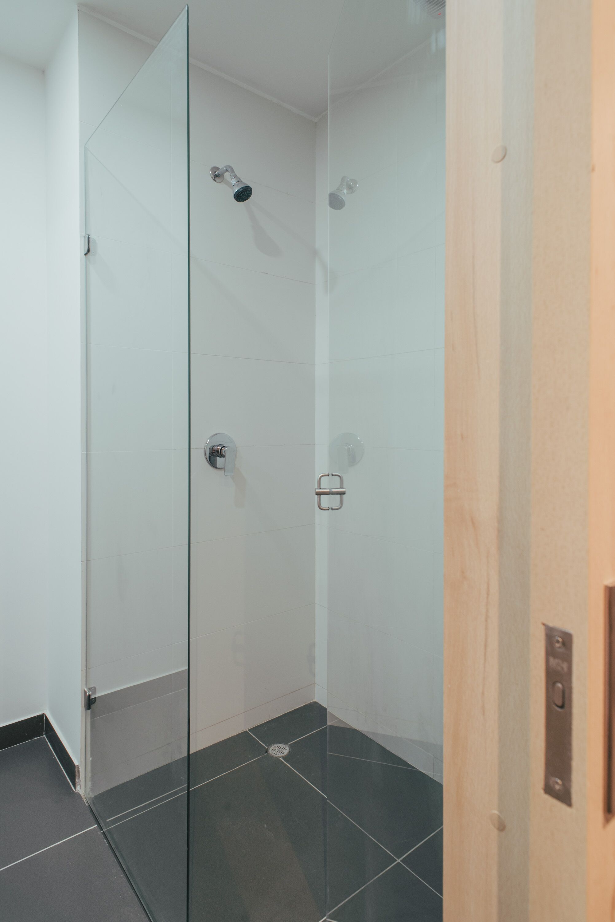 Une douche moderne avec une porte en verre, une porte en bois et un sol carrelé.
