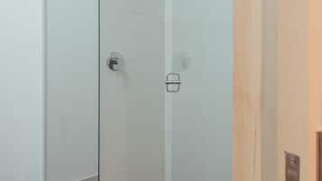 A modern shower with a glass door, a wooden door, and a tiled floor.