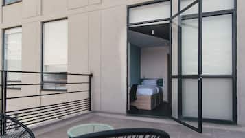 Una habitación de hotel moderna con balcón, una cama y una pequeña zona de estar.