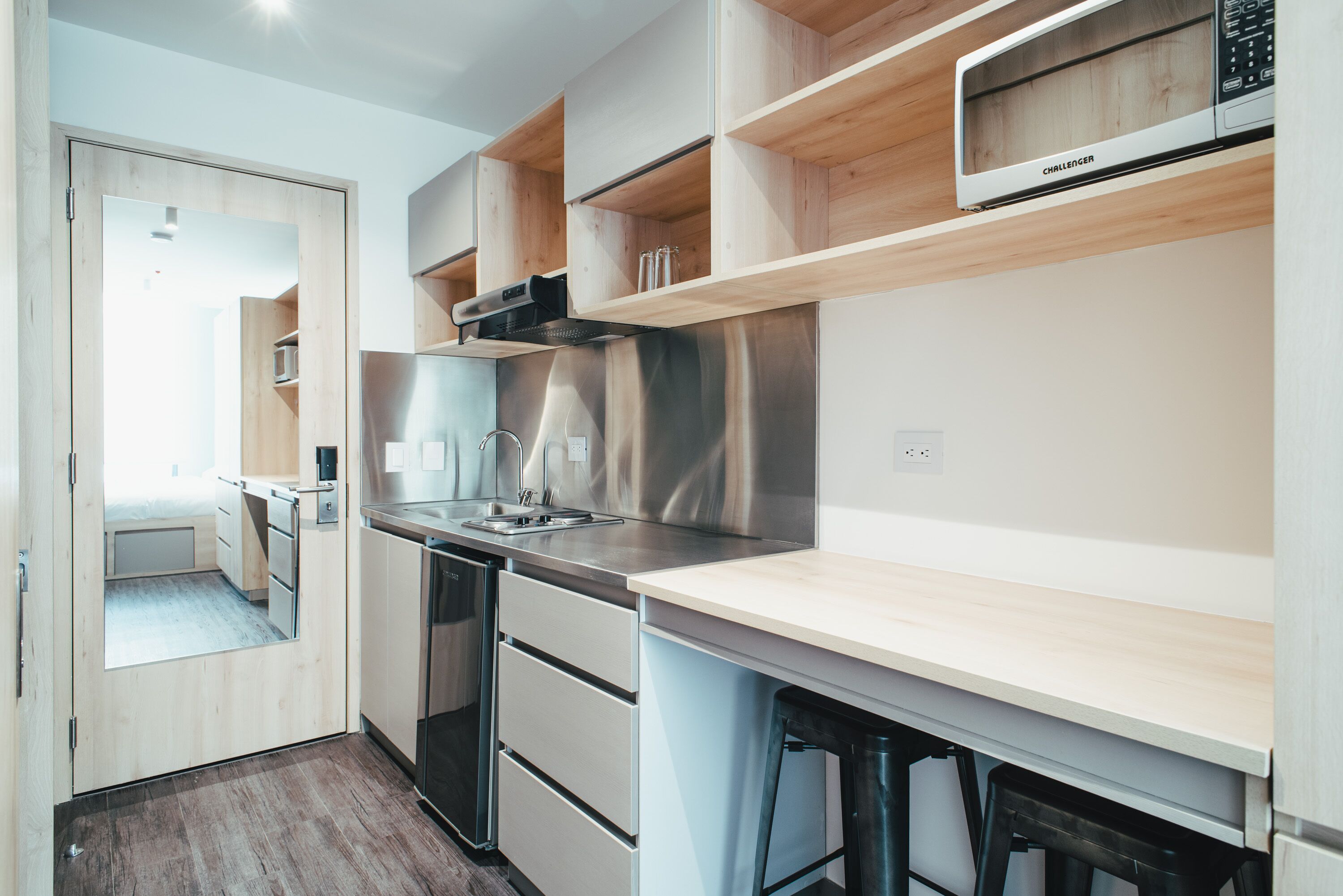 Una cocina moderna con electrodomésticos de acero inoxidable, estantes de madera y microondas empotrado.