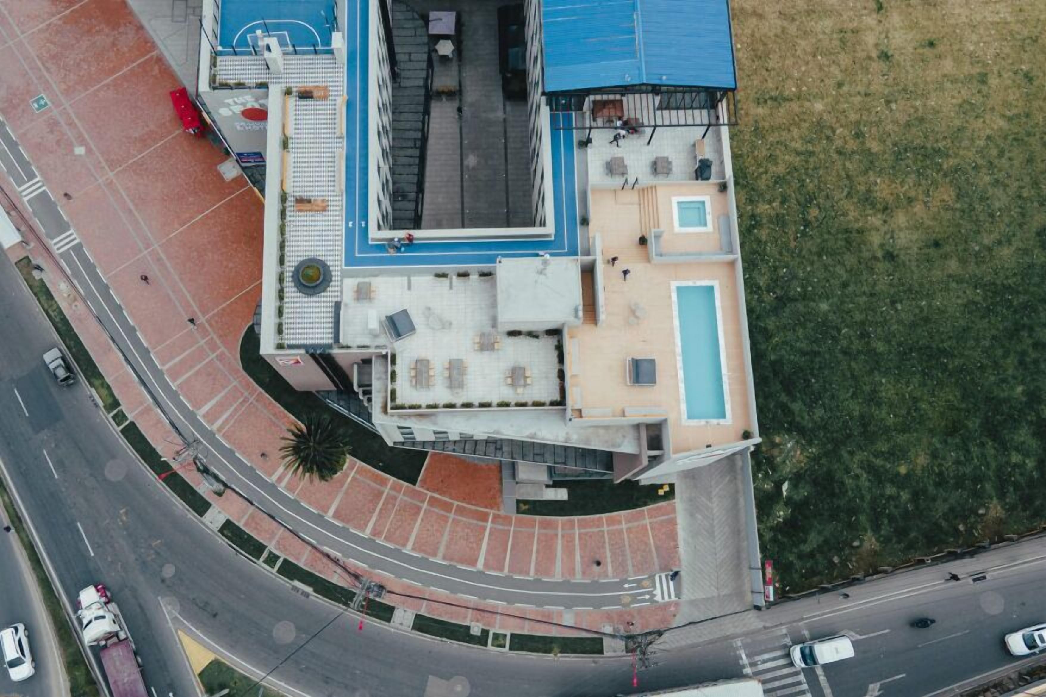 Luchtbeeld van een gebouw met een basketbalveld, een terras en een zwembad.