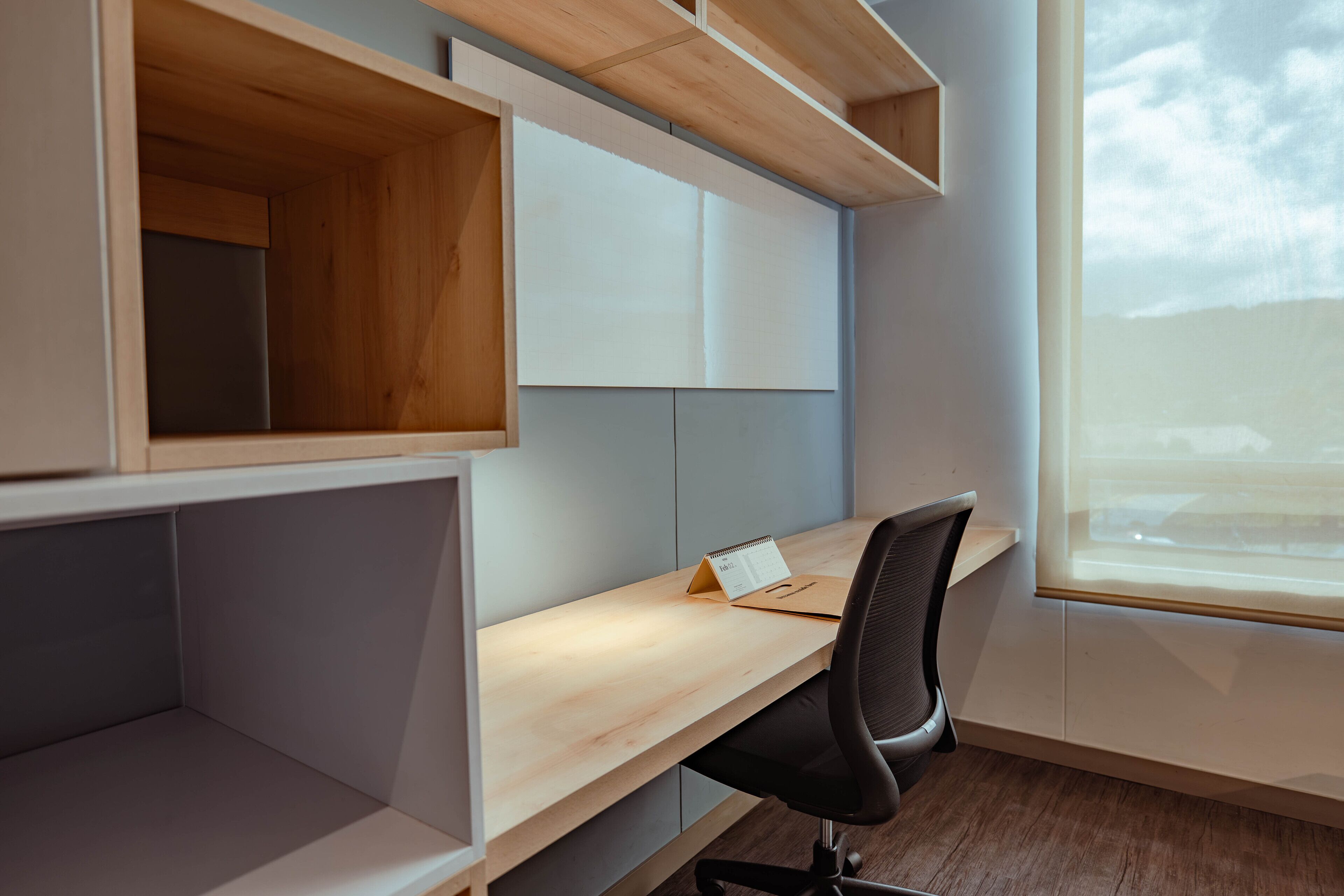A modern office space with a wooden desk, black office chair, and built-in shelving.