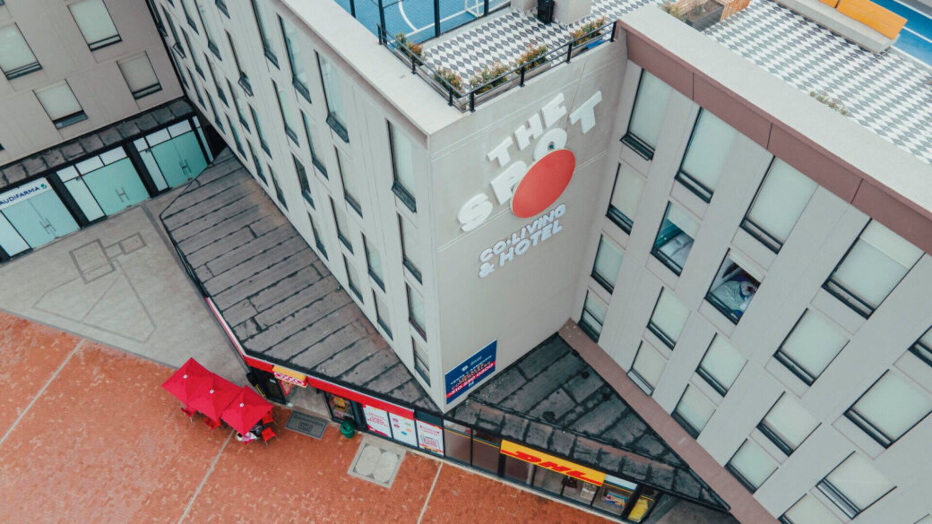 A modern building with a prominent sign for 'The St' hotel, featuring a red umbrella and a visible staircase leading to the entrance.