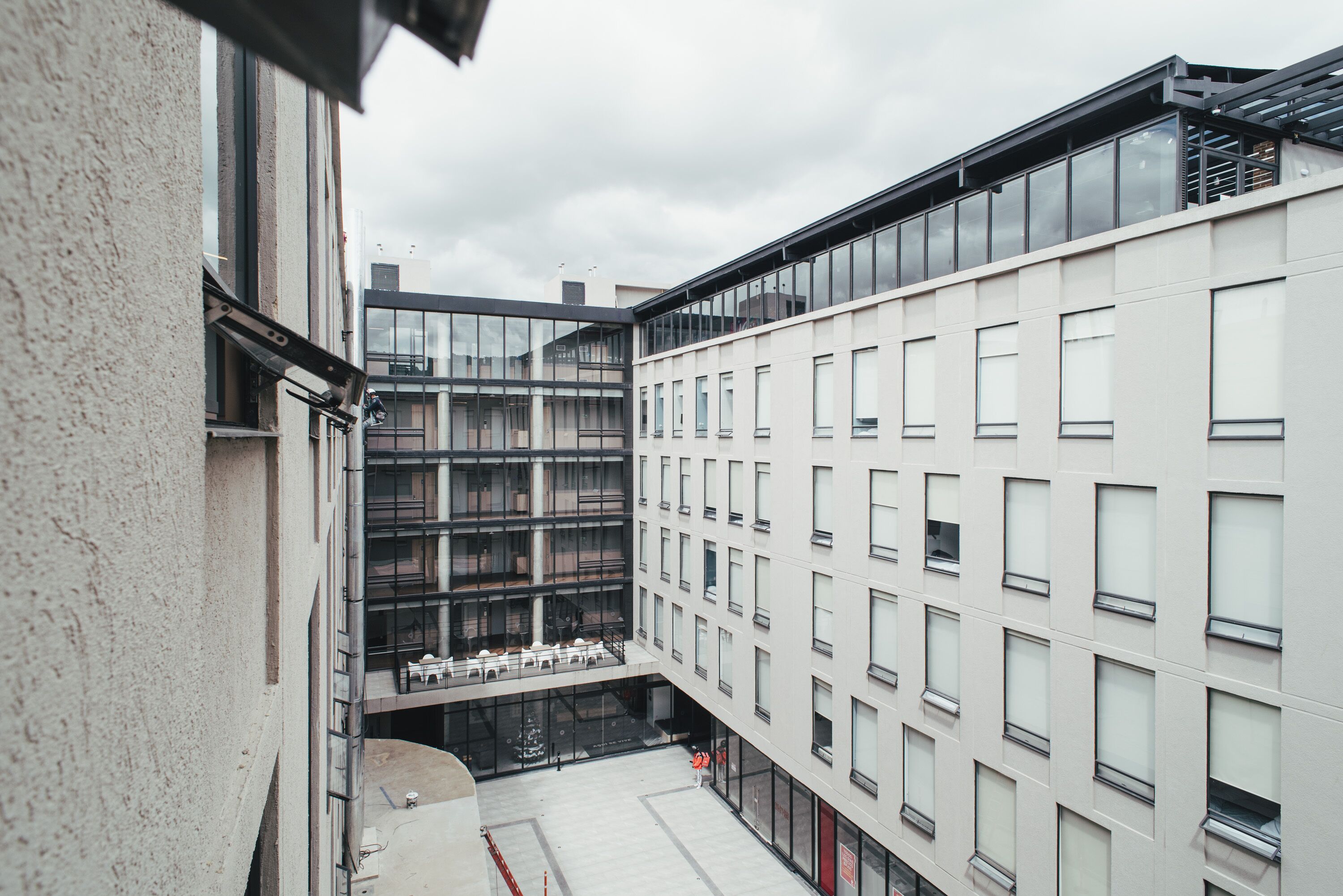 A modern building with multiple floors, large windows, and a courtyard area.
