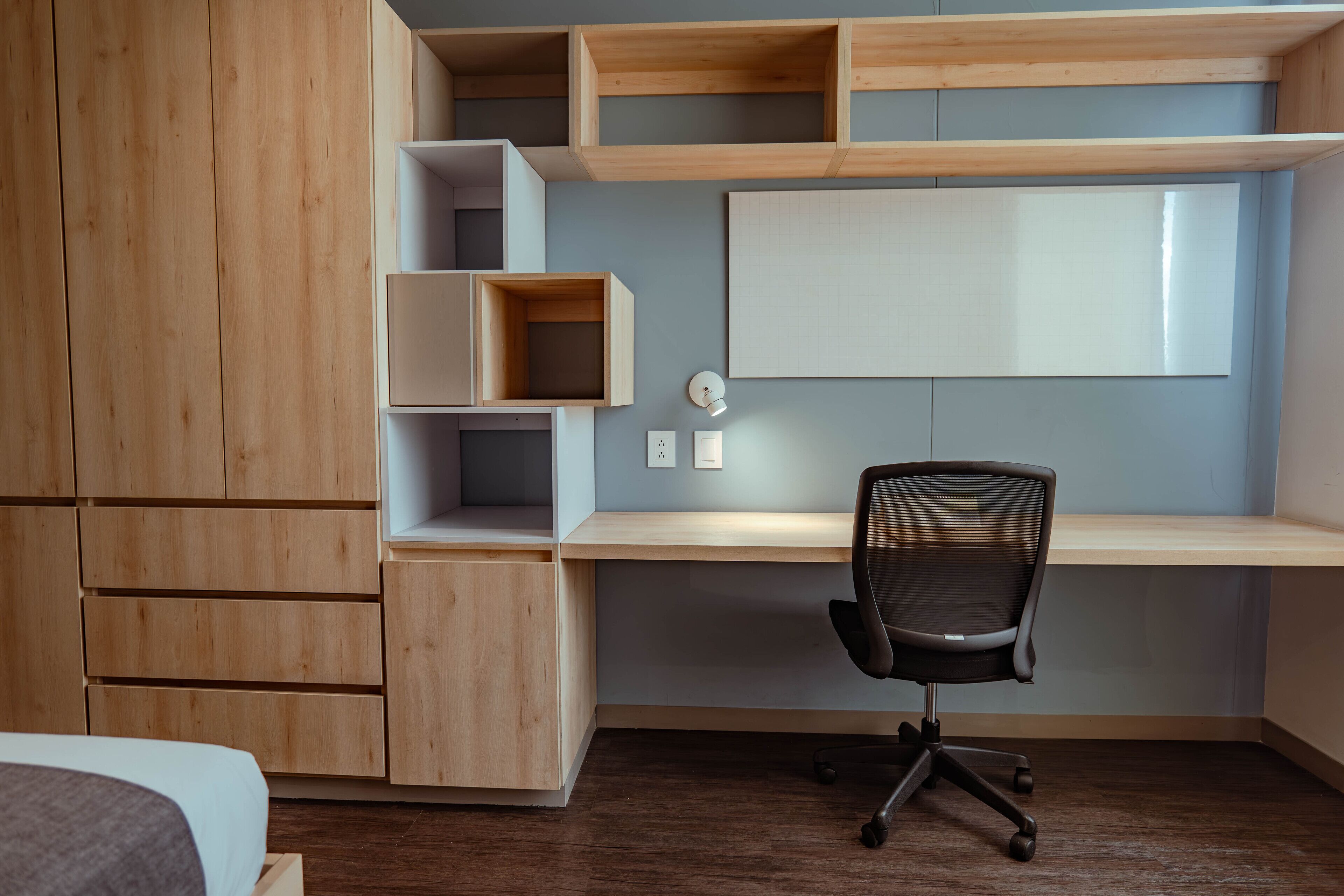Un dormitorio moderno con un armario de madera, un escritorio con silla y una cama.