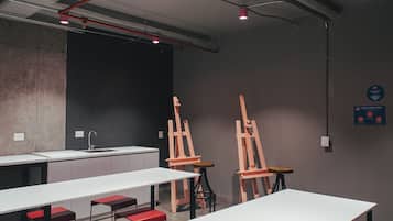 Una galería de arte moderno con mesas blancas, bancos rojos y caballetes.