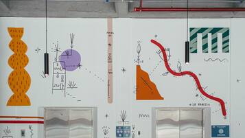 An elevator with a metallic interior and a wall with various abstract drawings and designs.