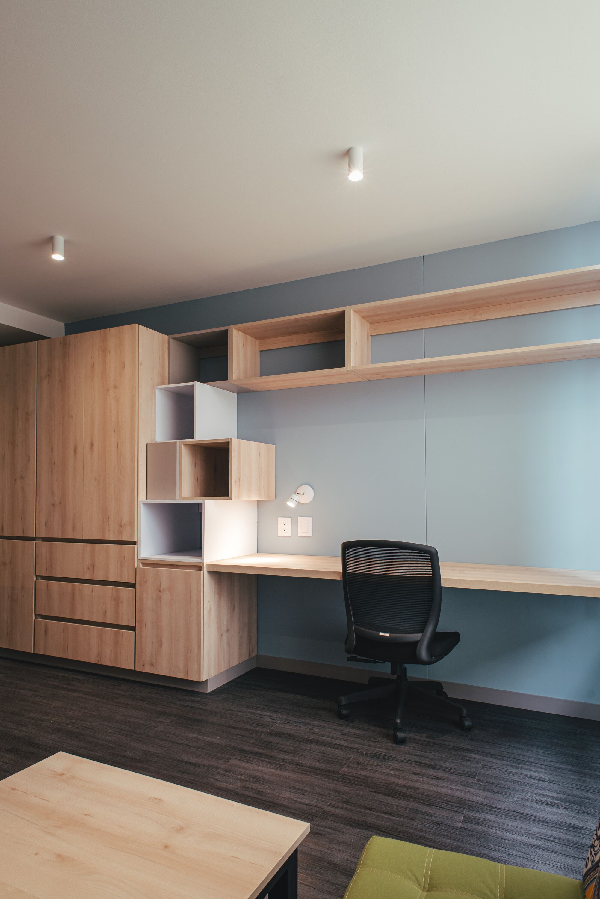 Un espacio de oficina moderno con un escritorio de madera, una silla de oficina negra y estanterías empotradas.