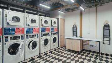 A laundry facility with multiple washing machines, a sink, and a tiled floor.