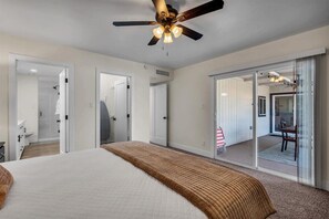 Relax in this inviting hotel room featuring a large bed, ceiling fan, and balcony access.