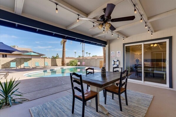 Relax by the pool in a shaded outdoor space with a dining area and comfortable seating.