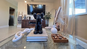 Una sala de estar moderna con suelo de mármol, un televisor plano grande, un aparador de madera y una escultura decorativa de un elefante.