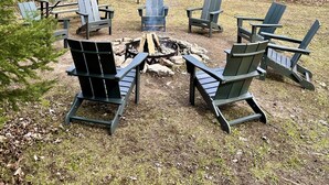 Une zone boisée avec un foyer entouré de fauteuils Adirondack.