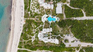 Vue aérienne d’un complexe hôtelier doté d’une piscine, d’un accès à la plage et d’une végétation luxuriante.