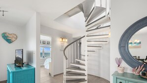 Escadaria em espiral em interior moderno, com vista para o exterior.