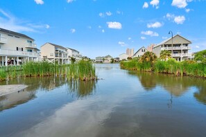 Un quartier résidentiel bordé de maisons, situé au bord d’un plan d’eau paisible, sous un ciel dégagé, sans aucune personne ni aucun élément de décoration visible.