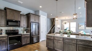 A modern kitchen with dark wood cabinets, stainless steel appliances, and a large island.