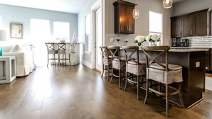 A modern kitchen with dark wood cabinets, a central island with bar stools, and pendant lighting.