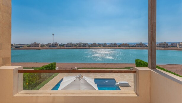 Ein Balkon mit Blick auf ein großes Gewässer, einen Pool und eine Stadtlandschaft in der Ferne.