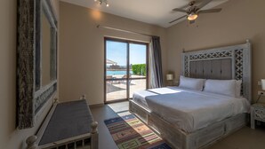 Ein Schlafzimmer mit einem großen Bett, einem Deckenventilator und Blick ins Freie.