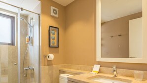 Ein modernes Badezimmer mit Duschkabine aus Glas, Toilette, Waschbecken mit Spiegel und Handtuchhalter.