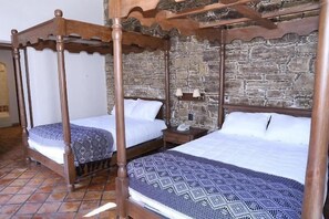 A four-poster bed with a stone wall backdrop, two bedside tables, and a patterned bedspread. - Hotel San Francisco Tlaxcala (Tlaxcala)
