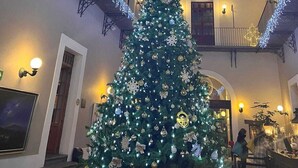 A grand hall with a large Christmas tree decorated with ornaments and lights, a geometric stained glass ceiling, and a staircase with railings. - Hotel San Francisco Tlaxcala (Tlaxcala)