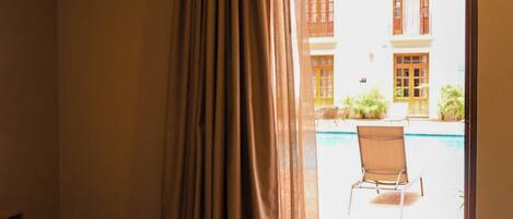 A hotel room with a bed, a tray with breakfast items, and a view of an outdoor pool area.