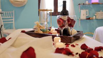 Ambiente romántico con una vela, pétalos de rosa y una botella de vino sobre una bandeja.