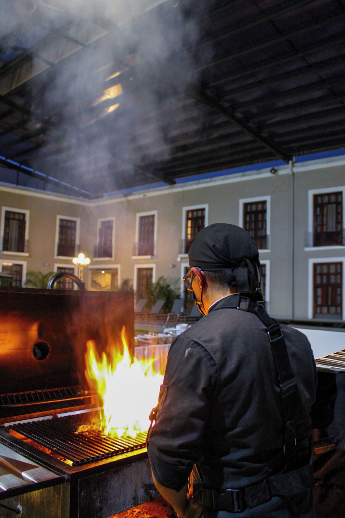 A chef grilling outdoors with a traditional building in the background.