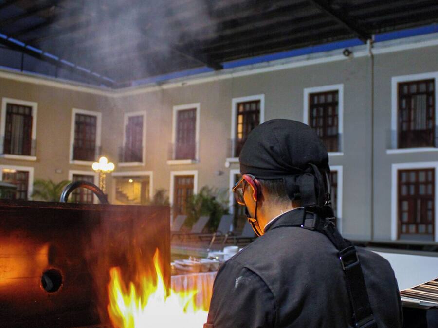 A chef grilling outdoors with a traditional building in the background.