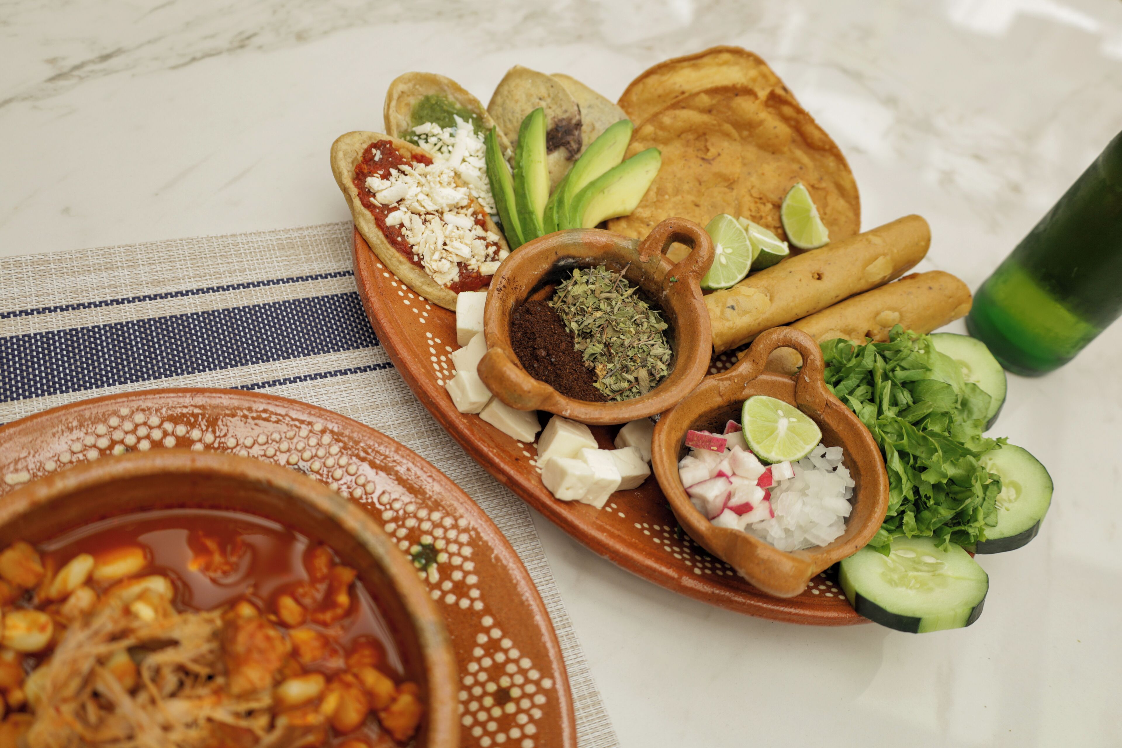 Une assiette contenant divers aliments, notamment des tortillas, de l’avocat, du fromage et du citron vert.