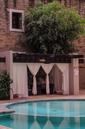 A pool area with a pergola, white curtains, and a brick wall. - Hotel San Francisco Tlaxcala (Tlaxcala)