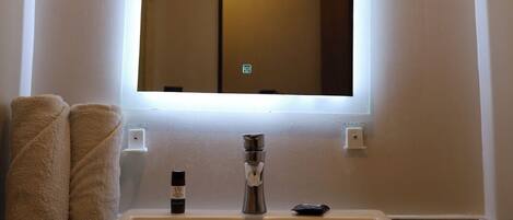 A bathroom with a large mirror, a sink, and two towels on the counter.