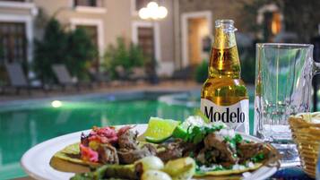 Una mesa de comedor con un plato de comida, una botella de cerveza Modelo y un vaso.