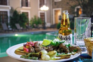 Una mesa de comedor con un plato de comida, una botella de cerveza Modelo y un vaso.