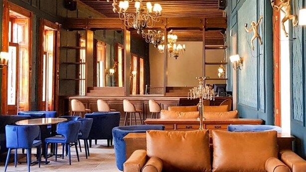 A cozy lounge area with a wooden ceiling, blue walls, and a chandelier. There are blue chairs and a brown sofa. - Hotel San Francisco Tlaxcala (Tlaxcala)