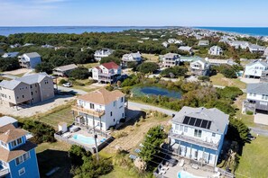 Vue aérienne d’un quartier résidentiel avec des maisons, une piscine et un petit étang.