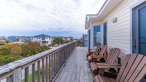 A wooden deck with Adirondack chairs and a view of houses in the background. - Gorgeous! Private Pool, Hot Tub, Game room, Family Friendly, D0115 (Duck)