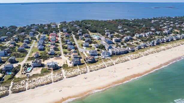 An aerial view of a coastal residential area with houses, a beach, and a large body of water. - Gorgeous! Private Pool, Hot Tub, Game room, Family Friendly, D0115 (Duck)
