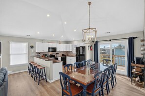 A modern kitchen with a central island, dining table, and chairs.