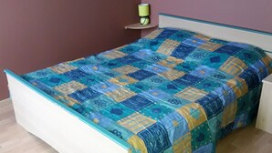 Una cama individual con una colcha estampada en una habitación con suelo de madera y pared morada.