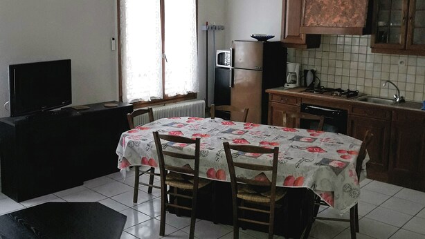 Una cocina compacta con comedor, un televisor negro y un reloj en la pared.