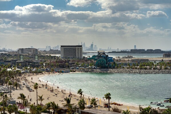 A beach with palm trees, a sandy shore, and a large water body. - Hyatt Centric Jumeirah Dubai (Dubai)