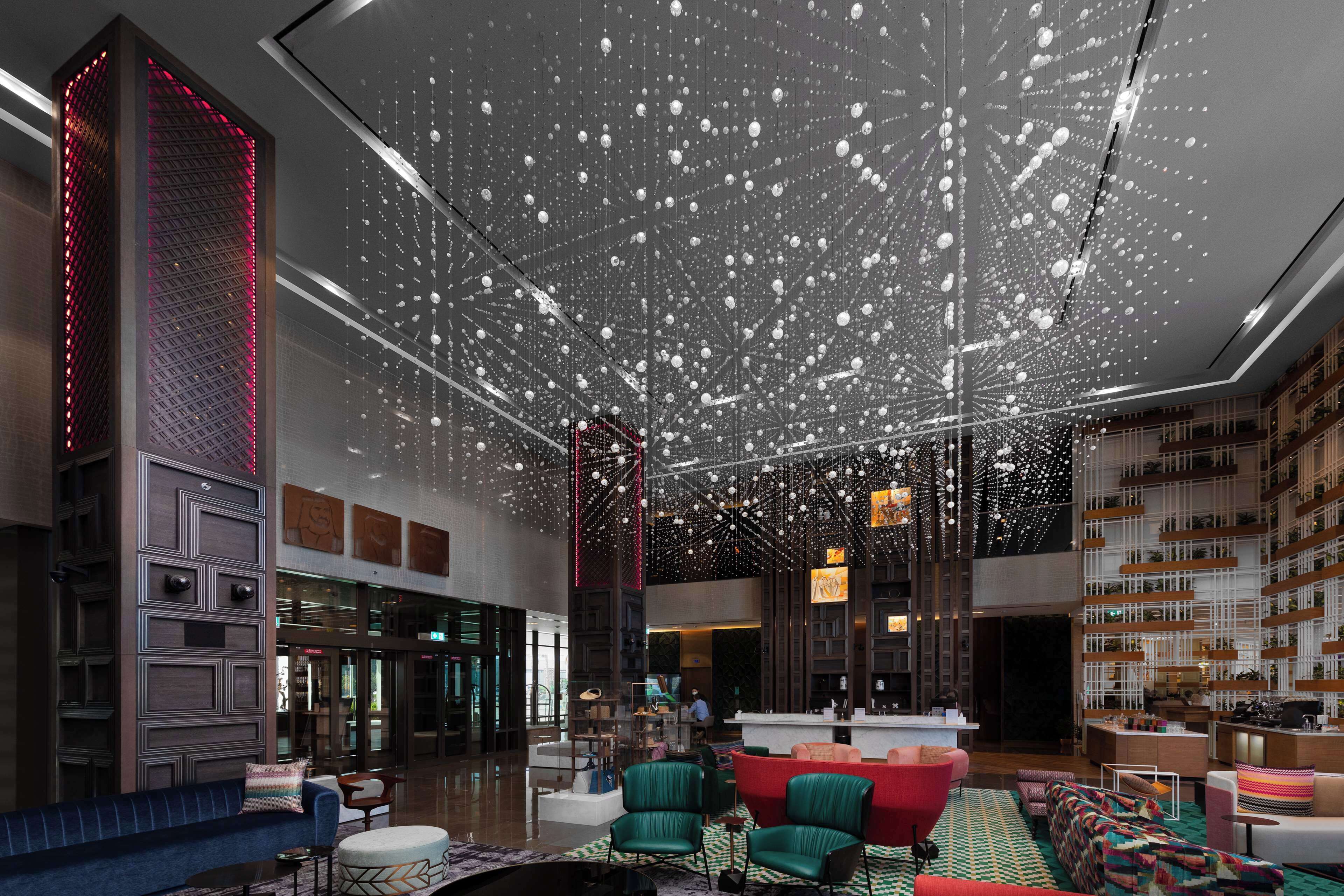 Een ruime lobby met een hoge plafond, modern meubilair en een centraal gelegen zithoek.